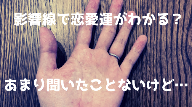 影響線 恋愛 手相 異性 結婚 運命線　手の写真　指輪をしている　木目の机